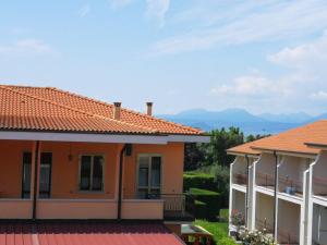 a house with an orange roof with mountains in the background at Cabà Holiday Bardolino Gritti in Bardolino