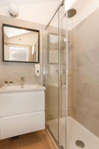 a bathroom with a shower and a sink and a mirror at Apartments and Rooms Stone House in Split