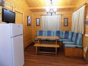 - un salon avec un canapé, une table et un réfrigérateur dans l'établissement CABAÑAS DE MADERA LA FLORIDA, à Arroyo Frío