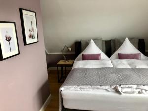 a bedroom with a white bed with pink pillows at Boutique Hotel Lindenhof, Bed & Breakfast in Aurich