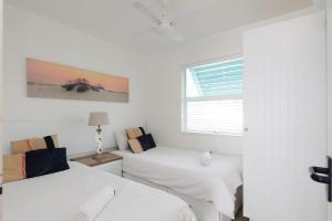 a white room with two beds and a window at Chakas Cove 39 in Ballito