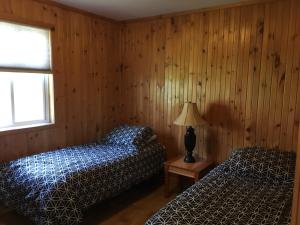 two beds in a room with wooden walls at Merland Park Cottages and Motel in Picton