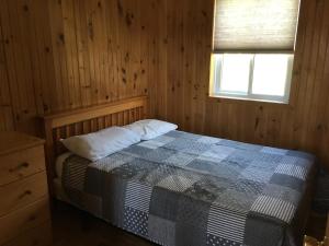 a bedroom with a bed in a wooden room at Merland Park Cottages and Motel in Picton