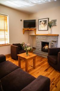 een woonkamer met een open haard en een televisie bij Piper's Chair Houses in Doolin