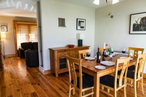 uma sala de jantar com uma mesa de madeira e cadeiras em Piper's Chair Houses em Doolin