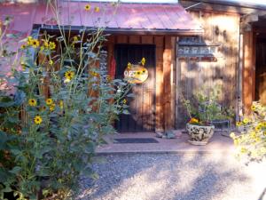 een voordeur van een houten huis met bloemen bij Silver River Adobe Inn Bed and Breakfast in Farmington