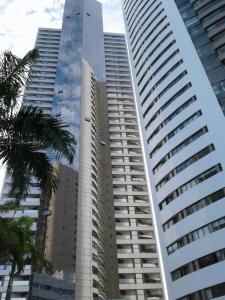 un edificio alto con palmeras delante en Betel Beach Flat Internacional Boa Viagem, en Recife