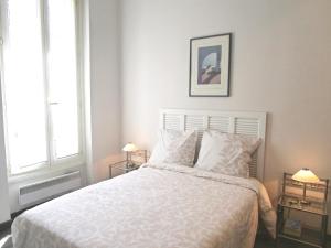 um quarto com uma grande cama branca e 2 candeeiros em Appartement em Nice