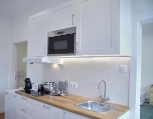 eine weiße Küche mit einer Spüle und einer Mikrowelle in der Unterkunft Ribeira Funchal Center in Funchal
