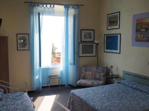 a bedroom with a bed and a chair and a window at hotel albatros in Arenzano