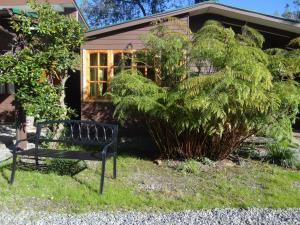 a black bench sitting in the grass in front of a house at Silvestre Cabañas in Puerto Varas