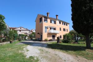 duży różowy dom z drzewem przed nim w obiekcie Apartments Rosanna w Rovinj