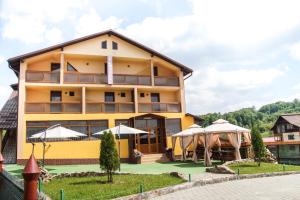 a large yellow building with umbrellas in front of it at Pensiunea Nicol in Valea Iasului