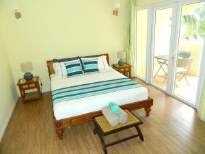 1 dormitorio con 1 cama grande y balcón en ARIEL BEACH VILLA*, en Grand Baie