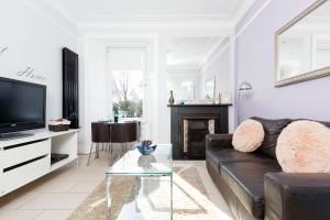a living room with a black leather couch and a tv at Edinburgh Near Centre Luxury Apartment in Edinburgh