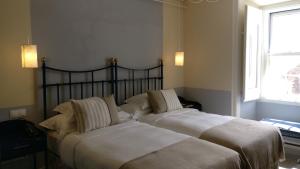 オビドスにあるPousada Vila Óbidosの窓付きのベッドルームにベッド2台が備わります。