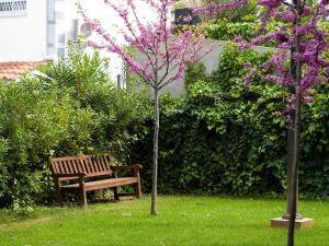 un banco de parque junto a un árbol con flores púrpuras en SG Costa Barcelona Apartments, en Castelldefels