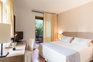 a bedroom with a bed and a desk and a television at Hotel Aquadulci in Chia