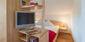 a small room with a television on a table with a bed at Pension Zum Ebenstein am Donausteig in Untergriesbach