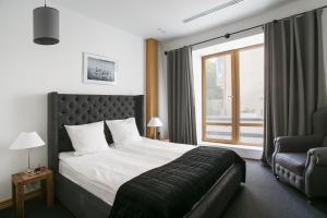 a bedroom with a bed and a chair and a window at Wall Street - Maestro in Odesa