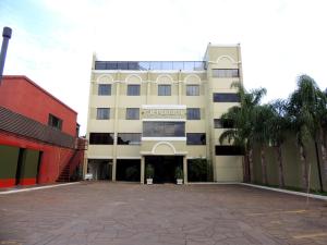 a large white building with a courtyard in front of it at Al-Manara Hotel in São Borja