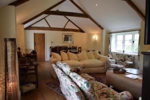 a living room with couches and a table and windows at The Barn, Ridouts Farm in Hazelbury Bryan