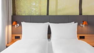 - 2 lits avec des oreillers blancs dans une chambre dans l'établissement Holiday Inn Munich - Leuchtenbergring, an IHG Hotel, à Munich