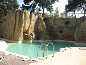 a large swimming pool with a rock wall at Residence Casale Verderame in Trapani