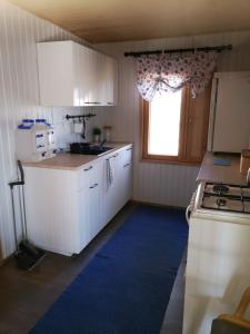 a kitchen with white cabinets and a blue rug at ILO107 in Huhus