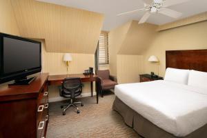 a hotel room with a bed and a desk with a television at American Inn of Bethesda in Bethesda