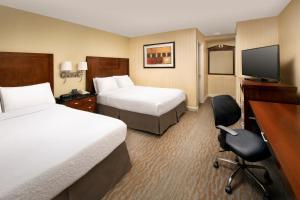 a hotel room with two beds and a desk and a chair at American Inn of Bethesda in Bethesda