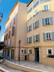 a large yellow building with green shuttered windows at Matelotte in Saint-Tropez