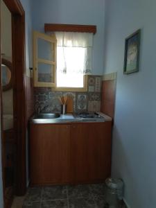 Elle comprend une petite cuisine avec un évier et une fenêtre. dans l'établissement Country Studios, à Karpathos