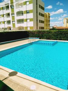 une grande piscine bleue en face d'un bâtiment dans l'établissement Apartamento Jardin II, à Gandía