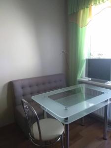 uma mesa de vidro com uma cadeira e um sofá em UpTown-Квартира em Vyshhorod