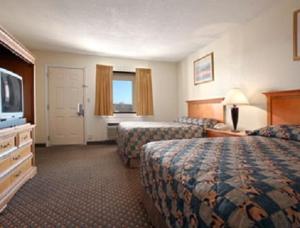 a hotel room with two beds and a flat screen tv at Park Hill Inn and Suites in Oklahoma City