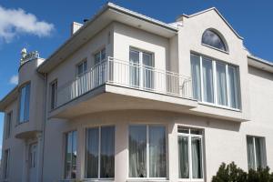 a white house with a balcony on top of it at Baltas Namas in Palanga