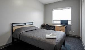 a bedroom with a bed and a desk with a computer at Residence & Conference Centre - King City in King City