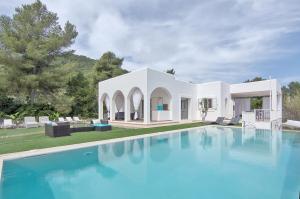 a villa with a swimming pool in front of a house at Can Garchet White Ibiza in Sant Jordi