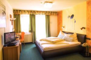 a hotel room with a bed and a television at Gästehaus Götz in Drobollach am Faakersee