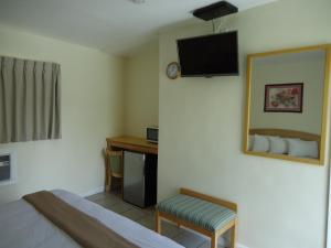 フォート・ローダーデールにあるCrown Innのベッド、デスク、テレビが備わるホテルルームです。