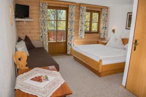 a bedroom with a bed and a couch and a window at Pension Schmiderer - Vorderkasbichlhof in Saalfelden am Steinernen Meer
