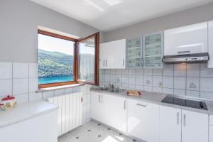 a kitchen with white cabinets and a large window at Apartments Alenka by the sea in Labin