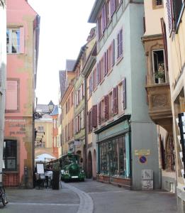 a city street with buildings and a green car at " Martin Schongauer " in Colmar