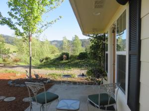 a patio with chairs and a view of a yard at Charming, Private Cottage in Myrtle Creek in Myrtle Creek