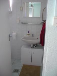 a white bathroom with a sink and a mirror at Jómadarak Nyaralója in Veresegyház