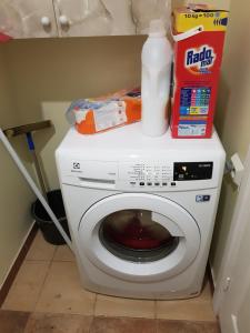 a white washing machine with a pile of cleaning products on top at Zvaigžņu māja in Pāvilosta