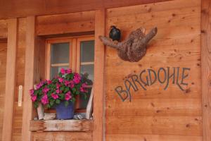 a sign on the side of a house with a window and flowers at Bergdohle in Adelboden