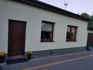 a white house with a brown door and two windows at Kwatera prywatna in Augustów