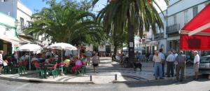 a group of people sitting at tables on a city street at Casa Neto Studio in Fuzeta
